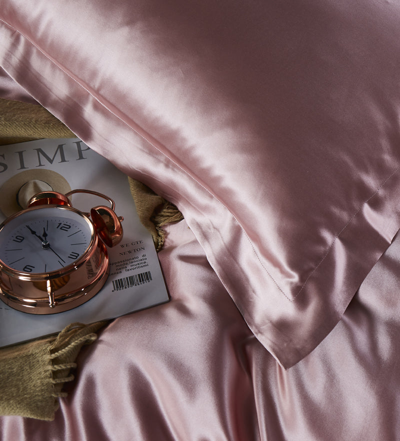 Pink satin pillowcase on a soft pink fabric background.