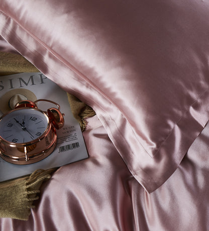 Pink satin pillowcase on a soft pink fabric background.